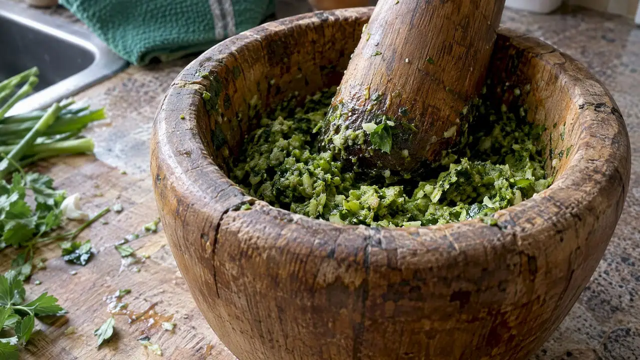 Thick green epis in a wooden mortar
